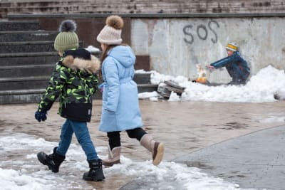 Barn i Butja, utanför Kiev, passerade en väggmålning av italienska Tvboy den 2 februari 2023. 