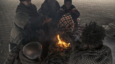 Hemlösa människor värmer sig vid elden en kylig morgon i Lahore i Pakistan.