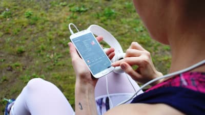 Tjej som kollar in löprunda på mobilen.
