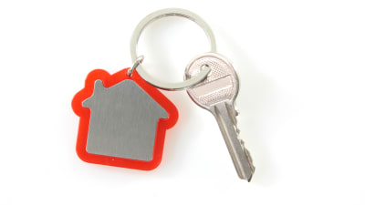 En nyckel fastsatt i en nyckelring som föreställer en stuga.