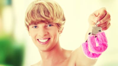 ung leende man håller upp rosa fluffiga handklovar