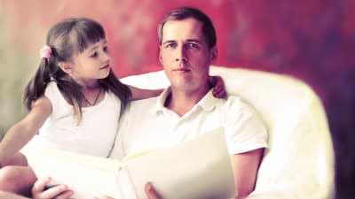Pappa läser högt till dotter. 