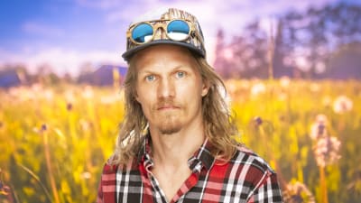 Kasper Ramström ser rakt in i kameran med en sommaräng som syns i bakgrunden.