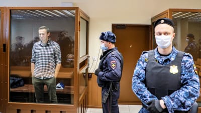 Navalnyi i glasbur vid rättegång, med beväpnade väktare.