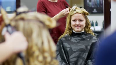 Nicole Nybergs blonda hår blir lockat av en frisörstuderande.