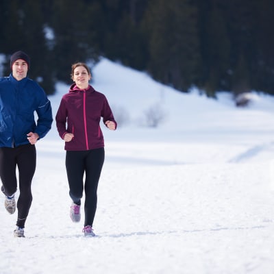 Två personer som ser glada ut, ute på en löprunda i snöigt landskap.