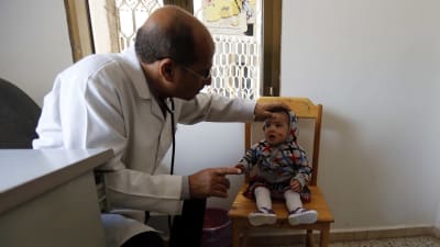 Ett litet barn med ett sår i ansiktet undersöks av en läkare på en mottagning.