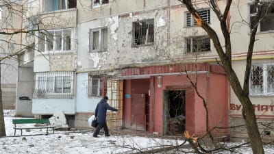 Mörkklädd person går in i ett lätt förfallet höghus i staden Ckarkiv. 