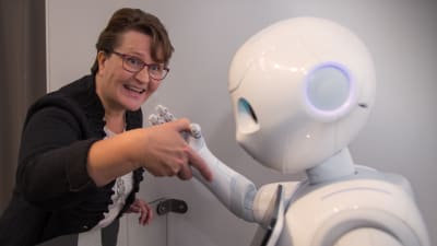 Riitta Bekkhus skakar hand med robot