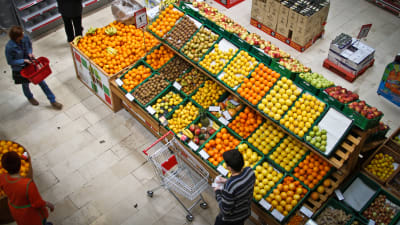 Folk handlar vid fruktavdelningen i en matbutik.