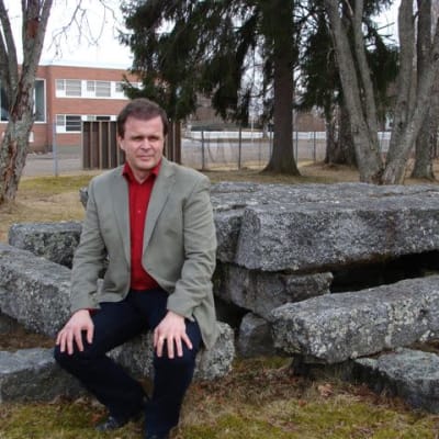 Kivijärven kunnanjohtaja Pekka Helppikangas istuu ulkona kivipenkillä.