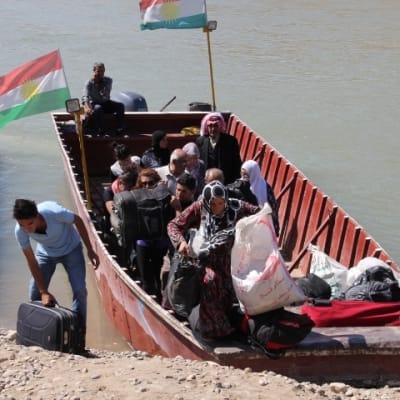 Syriska flyktingar tar i land vid en strand i Irak