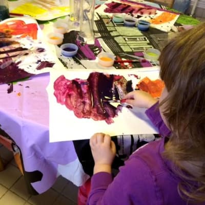 Lapsi maalaa vesiväreillä kirkkaita värejä