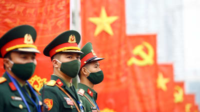 Soldater i förgrunden. I bakgrunden Vietnams och kommunistpartiets flaggor.