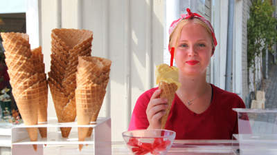 ung kvinna står bakom disk i glasskiosk och håller i en glass.