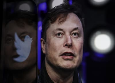Elon Musk tittar uppåt och framåt. Bredvid honom en logo av Twitter.