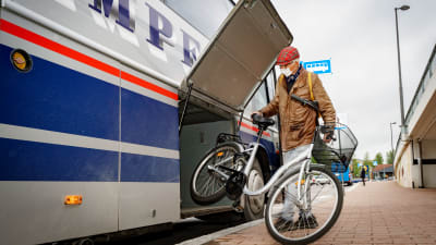 En man lyfter in en cykel i bussens bagageutrymme.