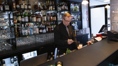 Bartender blandar en drink bakom bardisken på ett hotell.  
