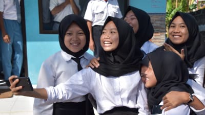 Malaysiska skolbarn tar en gruppselfie utanför sin skola.