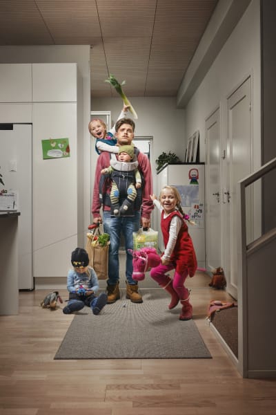 en pappa ser utmattad och står med tre barn i tamburen