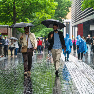 Ihmisiä kävelee kadulla sateenvarjojen kanssa