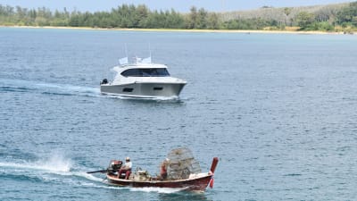 Snabbgående båt och fiskebåt i Thailand.