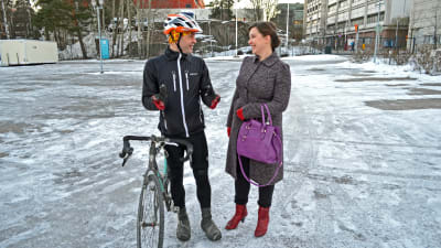 Fritjof Sahlström och Charlotte Vainio står vid hans cykel på parkeringsplatsen.