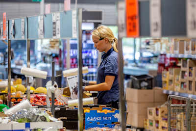 En person i Lidl-uniform packar upp frukt i en mataffär.
