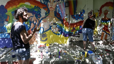 Deltagare i årets pridefestival i Istanbul målar regnbågens färger på en vägg under ett evenemang.