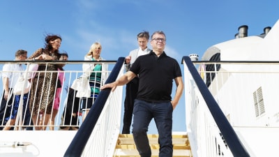 Petteri Orpo och hans partiledning på ett fartyg mot blå himmel