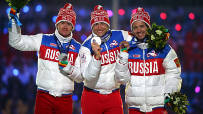 De ryska medaljörerna på femmilen i Sotji poserar på prispallen.