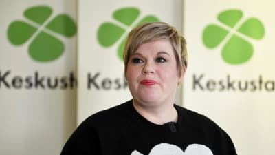 Annika Saarikko, taustalla keskustan banderolleja. 