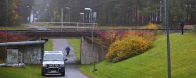 En polisbil står parkerad längs en cykelväg nära en mindre bro. 