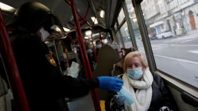 En polis delar ut ansiktsmasker till arbetare som måste på jobb i Spanien trots coronavirusåtgärderna.