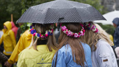 Flickor med blomsterkransar i håret under paraply