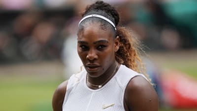 Serena Williams håller i sin racket och tittar nedåt.