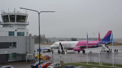 Wizz airs flyg i vitt, rosa och blått har landat på Åbo flygplats och folk håller på att stiga ur planet.