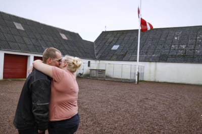 Minkfarmarna Peter och Trine Brinkmann Nielsen håller om varandra efter att ha hissat danska flaggan på halvstång på sin minkfarm i Boerglum Kloster på Jylland.