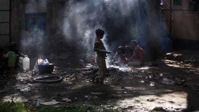 Hemlösa indier bränner skräp på en soptipp i Bombay.