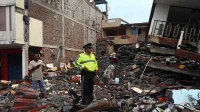 En polis står vid en husruin i den svårt drabbade kuststaden Pedernales dagen efter skalvet. 17.4.2016