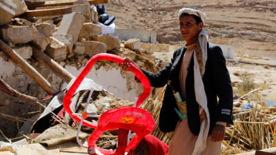 En yngling som överlevde attacken visar upp en barnstol från det totalförstörda, bombade huset