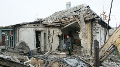 En kvinna hämtar saker ur sitt sönderskjutna hus i byn Jasinovataja i Donetsk-regionen den 21 december. Byn kontrolleras av proryska rebeller.