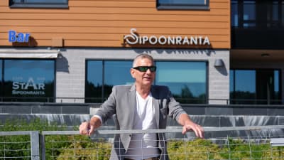 Ben Fuchs står bakom ett metallstaket framför Sibbostrand.