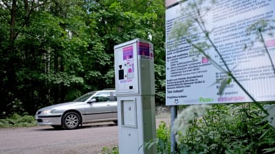 En bil kör förbi på vägen bakom den nya frivilliga parkeringsautomaten på Svinö.