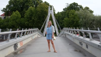 En kvinna står på en gångbro.