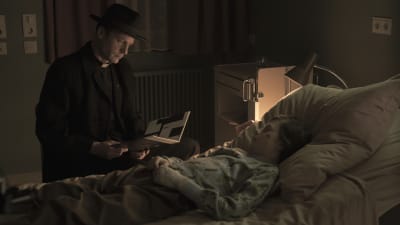 scen från den tyska TV-serien Dark, en man står vid en säng där ett litet barn ligger
