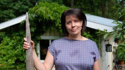 Hanne Aho står i sin trädgård framför ett hus.