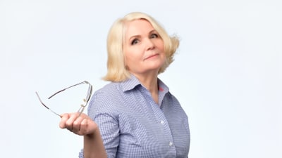 Uppgiven kvinna som håller i sina glasögon. 