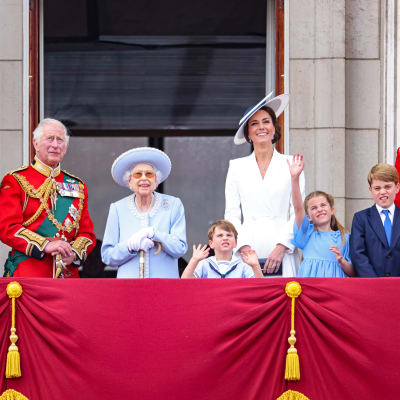 Brittiska kungafamiljen står uppradad på en balkong och vinkar åt folket.