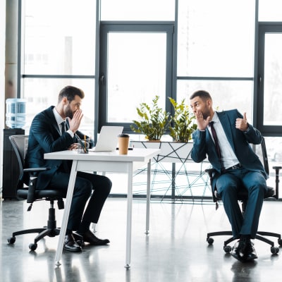 Två män i kostym sitter och skvallrar i modernt kontorsutrymme